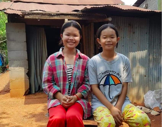 Srey-Neang-with-her-little-sister-in-front-of-their-house-531x415px