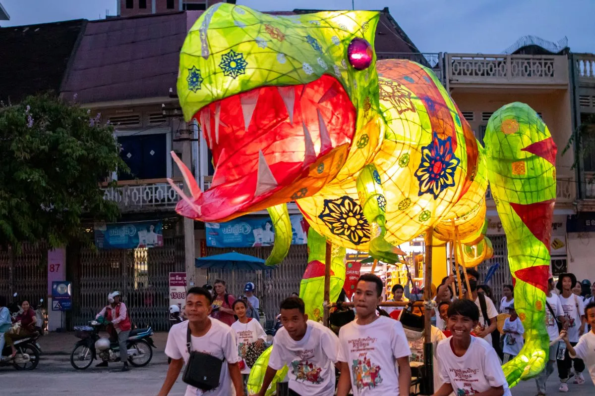 Volunteers pull a giant T-Rex puppet through the streets of Battambang as part of the art parade