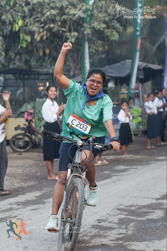 A cyclist cheers as she crosses the finish line during the Sangker River Run in Battambang, Cambodia